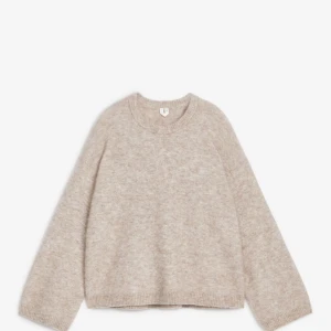 Beige stickad tröja från Arket - Supermjuk och fluffig beige stickad tröja från Arket med rund halsringning och långa ärmar. Perfekt för lager-på-lager och har en relaxed fit som ger en chill vibe. Ribbstickade muddar vid ärmslut och nederkant.