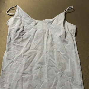 Blå Linne med smala band - Enkel och stilren blå linne med smala axelband och rak passform. Perfekt för varma dagar och lätt att matcha med accessoarer. Mjuk och bekväm känsla tack vare bomullsmaterialet.