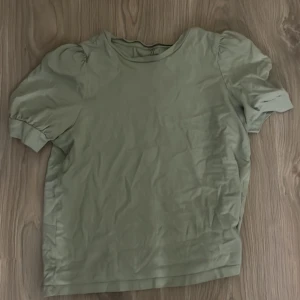 Grön puffärmad topp i bomull - Snygg ljusgrön topp med puffärmar och rund halsringning. Modellen är enkel men trendig och passar perfekt till jeans eller kjol. Tillverkad i mjuk bomull för en skön känsla. Perfekt för dig som gillar stilrena plagg med en twist.