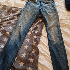 Crocker Boyfriend Jeans 25/32 - Säljer ett par ljusblå boyfriend jeans från Crocker i storlek 25/32. Jeansen har slitna detaljer på benen och klassisk femficksdesign. De är raka i modellen och har en avslappnad passform. Perfekta för en chill och trendig look.
