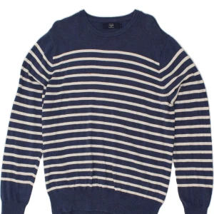 Randig blå tröja från J.Crew - Snygg blå tröja från J.Crew med vita ränder. Tröjan har rund halsringning och ribbade muddar. Tillverkad i mjuk bomull som känns skön mot huden. 