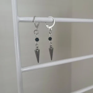 Silvriga örhängen med svarta pärlor - Coola örhängen i silverfärgad metall med hängande konformade detaljer och små svarta pärlor. Perfekt för dig som gillar edgy och unik stil. Säljs som ett par. I rostfritt stål och handgjort 