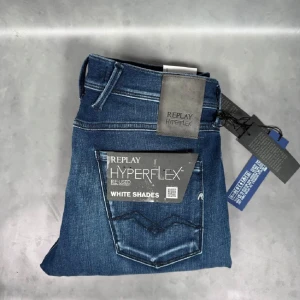 Replay Hyperflex blå jeans - Snygga Replay Hyperflex jeans i mellanblå tvätt med lätt slitning. Modellen har klassisk femficksdesign, normal passform och stretchigt material för extra komfort. Perfekta för dig som gillar stilrena och bekväma jeans med modern känsla.