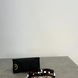 Svarta Ray-Ban solglasögon - Snygga svarta solglasögon från Ray-Ban med klassisk pilotform och mörka glas. Kommer med originalfodral i svart. Perfekta för att lyfta din stil under soliga dagar.