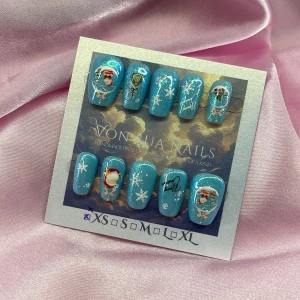 BlueXmas (XS); Short Coffin;Curved - *OBS! Mindre i storlek *Set med handgjorda lösnaglar i glittrande blått med julmotiv som tomte, snöflingor, granar och små hus. Naglarna har en kort coffin form och är mer kurvade, kan upplevas mindre i storlek. Setet har detaljer i vitt, rött och grönt. Perfekt för dig som vill ha unika naglar med vintertema. XS: 14 mm, 11 mm, 11,5 mm, 10 mm, 8 mm 