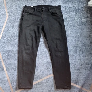 Svarta jeans från Zara, storlek 42 - Svarta jeans från Zara i klassisk femficksmodell med knappgylf. Jeansen har en rak passform och är tillverkade i ett mjukt denimtyg. Perfekta för dig som gillar stilrena och enkla byxor med modern känsla.