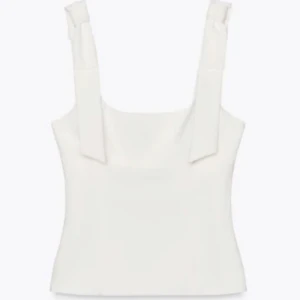 Vit linnetopp - Stilren vit linnetopp med breda axelband som knyts upptill. Toppen har en rak, något figurnära passform och är perfekt för en clean och modern look. Enkel att matcha med både jeans och kjol.
