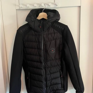 Svart cardigan från Zavetti Canada - Svart cardigan från Zavetti Canada med huva och snygga detaljer på axlarna.                                     • Skick: 9/10 • Storlek: S • Normal i storleken • Pris: 299 kr (öppen för bud 💬)  Skicka DM för fler bilder eller info! 🫱🏾‍🫲🏽