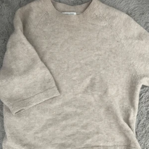 Beige stickad tröja & Other Stories - Mysig beige stickad tröja från & Other Stories med rund halsringning och halvlånga ärmar. Perfekt för lager-på-lager och enkel att matcha med både jeans och kjol. Superskön och stilren basic som funkar året runt. 