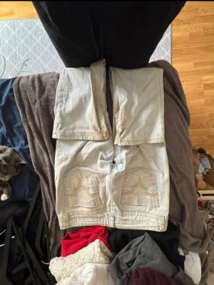 Ljusblå jeans med röda hjärtan - Säljer ett par ljusblå jeans från No Boundaries som jag köpte second hand i London, med unika röda hjärtan som jag målat dit själv på båda benen. Jeansen har klassisk femficksdesign, raka ben och är tillverkade i bomull med lite stretch för extra komfort. Perfekta för dig som vill sticka ut med en personlig touch.