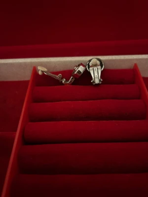 Silverfärgade örhängen med blå sten - Snygga clip-on örhängen i silverfärgad metall med rund, facetterad blå sten i mitten. Stenen har en intensiv blå färg som verkligen poppar och ger en cool touch. Perfekt för dig som vill ha statement-örhängen utan hål i öronen.