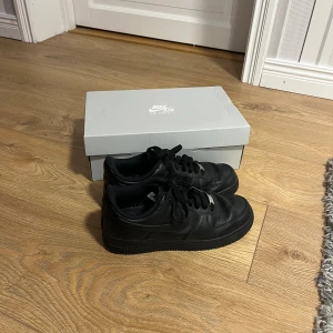 Nike Air Force 1 Svart Storlek 39cm - Ett par svarta Nike Air Force 1 som jag inte använt särskilt mycket men tillräckligt för att det ska vara synligt, dem är stora i storleken så om du har storlek 40 i skornså kommer dessa fortfarande passa