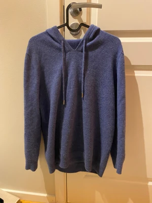 Blå merinoull hoodie - Säljer en blå stickad merinoull hoodie i storlek S. Den passar ca 167-180. Den är väldigt stretchiga och går lätt att vika upp. Köpte för 700kr för 3 månader sen. Den är i bra skick men lite noppig och har ett litet hål i ena armhålan.