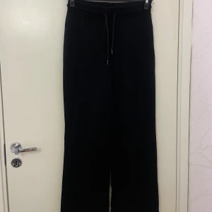 Svarta mjukisbyxor från 157, storlek S - Svarta mjukisbyxor från 157 i storlek S. Byxorna har en bred midja med snörning och raka, vida ben. Mjukt material som är skönt att ha på sig och passar perfekt för chill dagar. Enkel och stilren design utan synliga loggor eller detaljer.