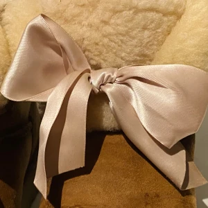 UGGs med rosett - Säljer mina bruna UGGs i storlek 39. Jättesköna och söta med en rosa silkesrosett på framsidan. Dom är unika eftersom dom inte tillverkas längre. Skorna är i fortfarande i relativt bra skick. 