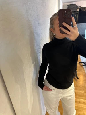 Svart polotröja från Gap, storlek S - Klassisk svart polotröja från Gap i mjukt stickat material. Tröjan har lång ärm och hög polokrage, perfekt för lager-på-lager. Enkel och stilren modell som funkar till allt. Säljes i storlek S. Några hål se sista bild