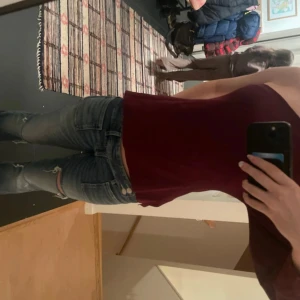 Vinröd oneshoulder topp från Zara - Säljer en vinröd oneshoulder topp från Zara i storlek S. Toppen har en lång ärm på ena sidan och är axelbandslös på andra, vilket ger en cool asymmetrisk look. Materialet är mjukt och stretchigt, perfekt för att sticka ut. Passformen är normal och färgen är djup vinröd.