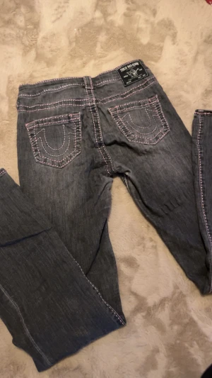 True religion med rosa stitching - Säljer dessa true religon för de aldrig kommit till användning. Slitage mellan benen (syns ej med byxan på) och längst ner i benen. Går lätt att sy eller lappa om man kan. De är mid Rise bootcut. 