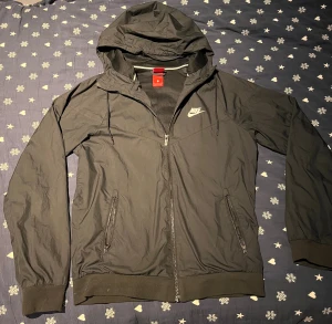 Svart Nike vindjacka med huva - Snygg vind jacka från Nike. Väldigt bra skick och använd ett fåtal gånger. Priset är ej hugget i sten så hör jättegärna va dig vid funderingar 🔥💯