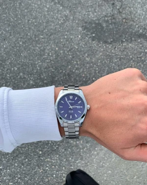 Blå och silverfärgad klocka från Doventi  - Stilren klocka från Doventi med blå urtavla och silverfärgat armband i metall. Klockan har en rund form, tydliga indexmarkeringar och datumvisning. Quartz-urverk och klassisk design som passar till många olika outfits. Perfekt för dig som gillar snygga accessoarer.