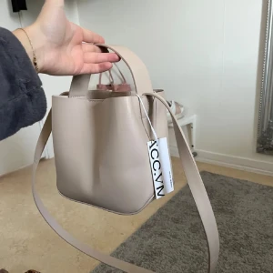 Beige väska från ACC.VN -  beige axelväska från ACC.VN. Väskan har både handtag och lång axelrem, samt ett praktiskt innerfack med dragkedja, en minimalistisk och clean väska perfekt för höst och vinter. Perfekt skick förutom att ja inte har prislappen som syns på första bilden.