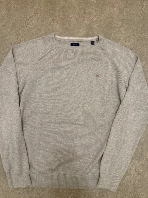 Gant Stickad Tröja  - Tja! Säljer denna stilrena gråa stickade gant tröjan! Storlek S - 176 cm  / Skick 10/10 nästan aldrig använd! Priset är ej hugget i sten, tveka inte att kontakta vid frågor eller funderingar!