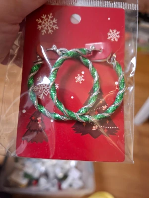 Glittriga juliga creoler örhängen - Säljer två par stora creoler med glittrigt spiral-mönster. Ena paret är grönt och silver, andra paret är rött, grönt och silver. Perfekta för att maxa julstämningen! Örhängena är metallfärgade med färgglada glitterdetaljer som verkligen poppar.