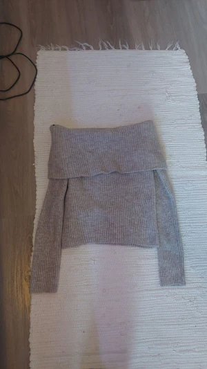 Grå ribbstickad offshoulder-tröja H&M - Säljer en helt oanvänd snygg grå-aktig ribbstickad offshoulder-tröja från H&M i storlek M. (Orginal pris 229kr) Tröjan har lång ärm och bred kant över axlarna som ger en cool offshoulder-look. Perfekt för dig som gillar stilrena och trendiga plagg med lite extra edge.