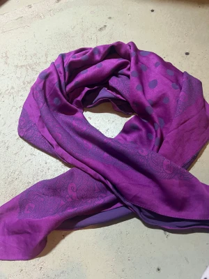 Lila prickig halsduk i silke - Snygg lila halsduk med mörklila prickar och diskret paisleymönster längs kanterna. Tunt och mjukt material som ger en lyxig känsla och snyggt fall. Perfekt accessoar för att lyfta din outfit med lite färg och mönster.