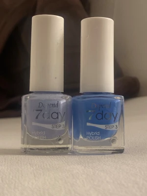 Depend 7day Hybrid Polish blå/lila - Två Depend 7day Hybrid Polish nagellack i snygga färger: en ljuslila och en klarblå. Båda kommer i stilrena glasflaskor med vita korkar och är märkta med 'Step 3'. Perfekt för dig som vill ha fräscha och trendiga naglar.