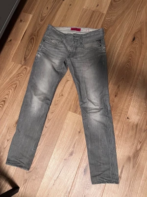 Replay Jeans - Säljer nu dessa gråa jeans från Replay. Jeansen är i modellen anbass. Storleken är W31 L32. Jeansen har slitna detaljer lite överallt vilket ger byxorna ett unikt och snyggt utseende. Byxorna är i schysst skick. Hör av dig vid minsta fundering!