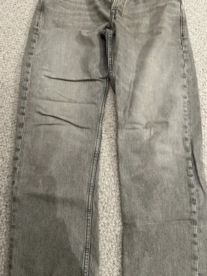 Jack & Jones jeans - Snygga grå jeans från Jack & Jones. Jeansen har klassisk femficksdesign och är tillverkade i slitstarkt jeanstyg. Perfekt för dig som gillar avslappnad stil och vill ha lite extra utrymme i benen.