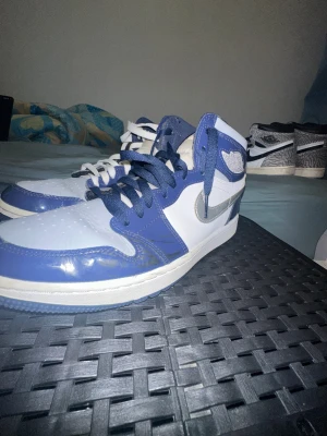 Nike Air Jordan 1 Golf blå/vit - Det här är inte bara ett par skor det är Air Jordan 1 Retro High Golf Patent Midnight Navy. En modell som sticker ut och är svår att få tag på i Sverige. Köpta på sneaker event i USA vilket gör dem till ett riktigt samlarobjekt eller perfekta vardagssneakers för dig som vill dra blickar nu under vinter mörkret eller perfekt julklapp👟.  Sparsamt använda, i fint skick med små märken som inte stör helhetsintrycket. (Skorna kommer med 2 olika skosnören, pga tidigare ägare)