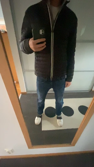 Svart pufferjacka från Colmar - Säljer en svart pufferjacka från Colmar med quiltad design och silverfärgad dragkedja. Jackan har lång ärm, ståkrage och Colmar-logga på ärmen. Materialet är syntet och jackan är perfekt för kyliga dagar. Snygg och stilren modell som funkar till jeans och sneakers.