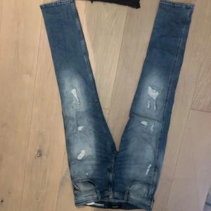 Replay Anbass Slim Fit blå jeans - Snygga Replay Anbass jeans i slim fit med slitningar och tvättad blå färg. Klassisk femficksmodell med läderpatch bak i midjan och diskreta röda detaljer vid bakfickan. Jeansen har smal passform och är tillverkade i mjukt denimtyg. De är knappt använda och sitter bra jag är 180 lång o de sitter perfekt.