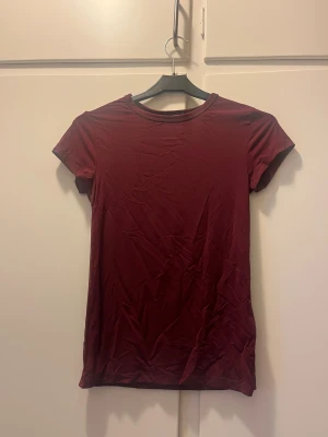 Mörkröd T-shirt i  från Lager157 - En jättefin, mörkröd tshirt inköpt från Lager157. Liten i storlek så skulle säga att den passar som XS eller S, trots att det står stl M. Materialet är stretchigt och känns som träningsmaterial, så är perfekt att både ha casual men också som ett snyggt träningsplagg! 