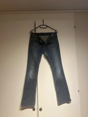 Low waist  jeans från Lee med bootcut - Snygga blå jeans från Lee med klassisk bootcut och raka ben. Jeansen har fem fickor och Lee-logga på bakfickan. Materialet är slitstarkt denim i bomull och färgen är en tvättad blå ton med lätt faded effekt.                                                             Jag är 168cm och de är i min smak lite för korta för mig också rätt stora i midjan.