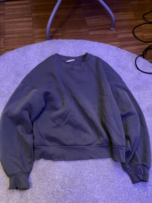 Grå sweatshirt med loose fit S - En enkel grå sweatshirt med loose fit och ribbade muddar vid ärmslut och nederkant. Tröjan har rund hals och långa ärmar, perfekt för chill dagar. Materialet känns mjukt och bekvämt mot huden.