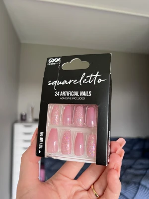’Squarelettoo’ Rosa glitter-lösnaglar (oöppnad) - 24 konstgjorda naglar i squareletto-form från OXX Cosmetics. Naglarna är ljusrosa med skimrande glittereffekt. Lim tillkommer i förpackningen. Oöppnad förpackning.