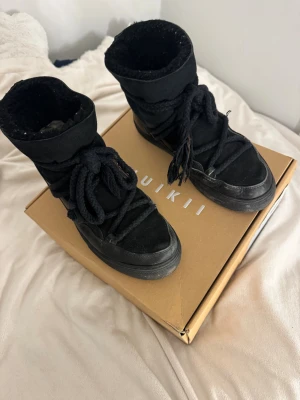 Svarta boots från Inuikii i storlek 40 - Säljer ett par svarta boots från Inuikii med grov snörning och rund tå. Utsidan är i mocka och insidan är fodrad med mjukt material för extra värme. Sulan är platt och robust, perfekt för kyliga dagar. Snygg och chunky look som passar till många stilar.💕💕