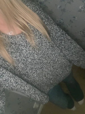 Svartvit stickad tröja från H&M - Mysig stickad tröja från H&M i svartvitt melerat garn. Tröjan har en bred rund halsringning, grovstickad struktur med kabelstickat mönster framtill och långa, lite loose ärmar. Perfekt för dig som gillar chill och oversized vibe.