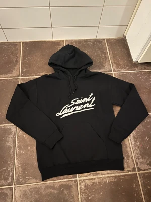 Saint Laurent hoodie  - Riktigt fet och eftertraktad hoodie med saint laurent loggan. Storlek S, skick 10/10!! Saknar lapp i nacken så är lite osäker på äktheten så därför är priset just nu på 999kr! Nypris runt 7000! Tveka inte med att ställa frågor!