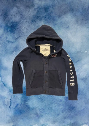 Vintage Hollister Cardigan Med Knappar - Säljer denna otroliga sällsynta och feta Hollister cardigan med knappar | I bra skick, tröjan är urtvättad men annars väldigt bra!| Längd ≈ 60cm, Bredd armhåla - armhåla 50 cm | Modell 175, 68 kg