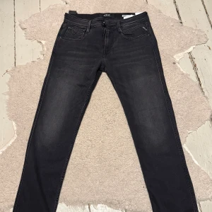 Replay Anbass svarta slim jeans - Svarta Replay Anbass jeans med slim fit och klassisk femficksdesign. Jeansen är tillverkade i stretch denim för extra komfort och har en snygg mörk tvätt. Passar dig som gillar en smal siluett och stilren look.
