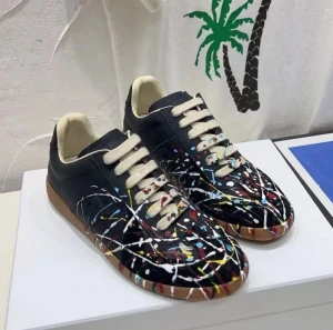 Maison Margela GAT - Unika margelas med coolt färgstänksmönster i vitt, rött, blått och gult. Skorna har rund tå, platt sula i brunt och vita snören. Tillverkade i skinn med en konstnärlig vibe som sticker ut i mängden.