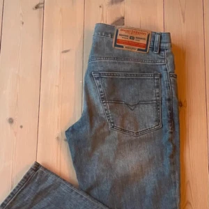 Blå jeans från Diesel W31 - Snygga blå jeans från Diesel i klassisk femficksmodell. Jeansen har raka ben, normal passform och är tillverkade i slitstarkt denim. Perfekta för dig som gillar en enkel och stilren look med diskreta detaljer och klassisk blå tvätt.