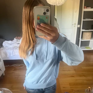 Ljusblå hoodie från 157, XS - Mysig ljusblå hoodie från 157 i storlek XS. Tröjan har huva med snörning, ribbade muddar och är tillverkad i mjuk bomullsblandning. Perfekt för chill dagar och enkel att matcha med jeans eller leggings.