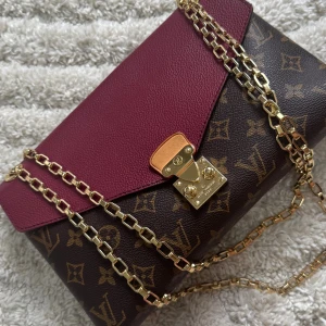 Louis Vuitton axelväska monogram vinröd - Snygg axelväska från Louis Vuitton med klassiskt monogrammönster i brunt och guldiga detaljer. Vet ej om äkta eller inte. Därför vill bara blir av med den.