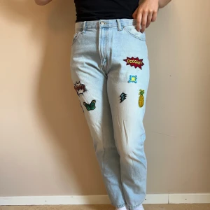 Ljusblå jeans med coola patches - Ljusblå jeans i denim med patches. Rak passform. Två av patchesarna sitter inte på men de skickas med. Går att fästa med lim eller att sy fast