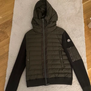 Mörkgrön Moncler Cardigan - Snygg mörkgrön Moncler Cardigan med stickade ärmar i storlek 1 (S). Jackan är perfekt till hösten och har inte använts innan. Kom PM vid funderingar